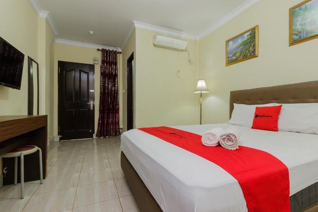 1 dormitorio con 1 cama grande con sábanas rojas y blancas en RedDoorz @ Malalayang 2 Manado, en Manado