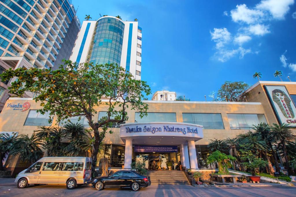 un edificio con dos coches estacionados frente a él en Yasaka Saigon Nha Trang Hotel & Spa, en Nha Trang