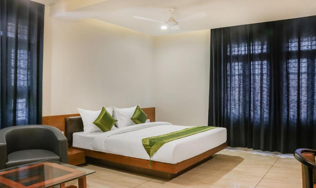 a bedroom with a bed and a chair and a table at Treebo Trend Casino in Kozhikode