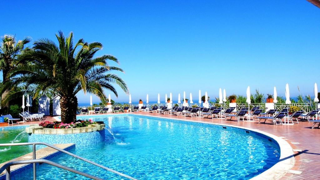 イスキアにあるParadiso Terme Resort & SPA con 5 piscine termaliのヤシの木と椅子が備わる大型スイミングプール