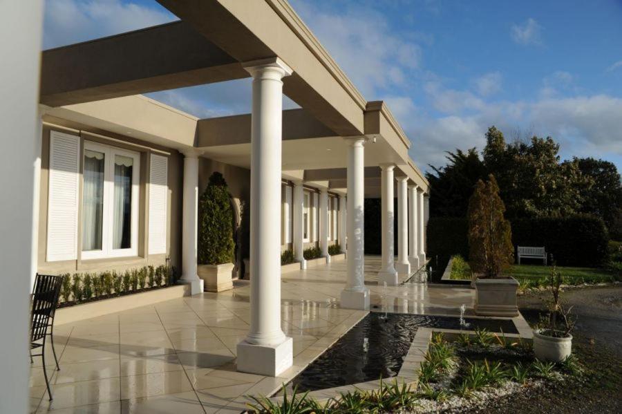 a house with columns and a pond in front of it at Norwood House Motel & Receptions in Mornington