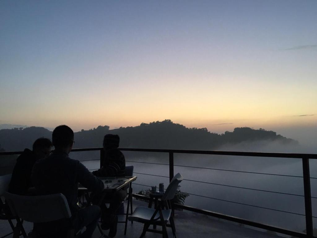 un grupo de personas sentadas en una mesa viendo la puesta de sol en 歐森View包棟Villa x 雲海夜景 x 獨立空間 en Dongshi
