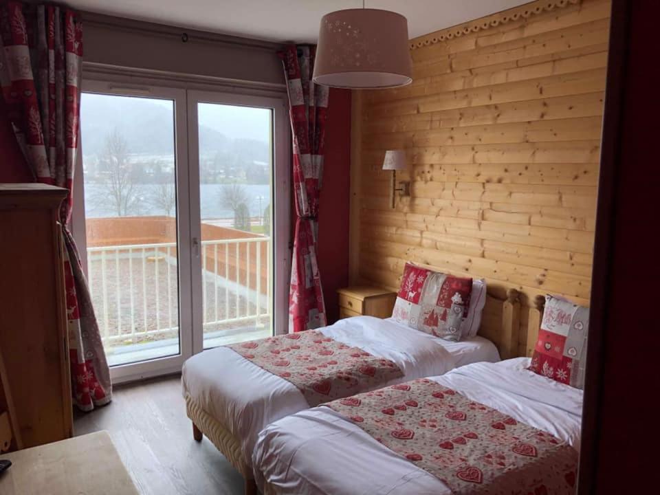 a bedroom with two beds and a large window at Le Ptit Hotel du Lac in Gérardmer