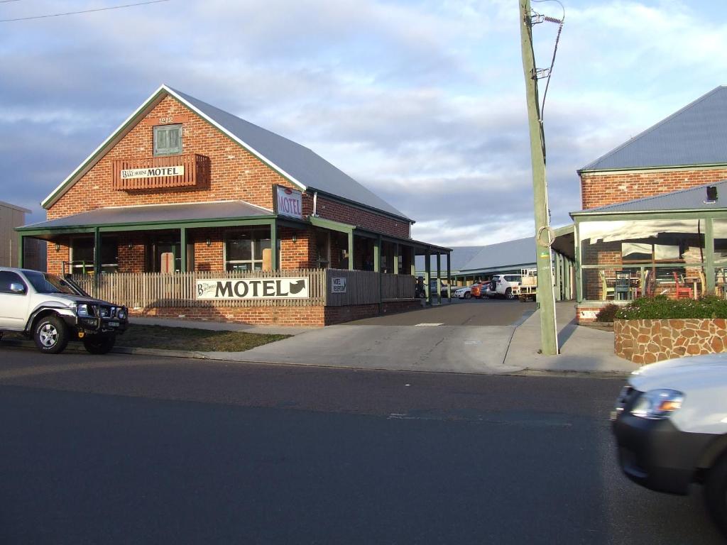 un edificio de ladrillo con un coche aparcado delante de él en The Bakehouse Motel, en Goulburn