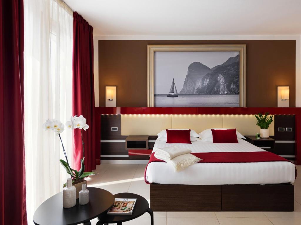 a bedroom with a large bed with red curtains at Kairos Garda Hotel in Castelnuovo del Garda