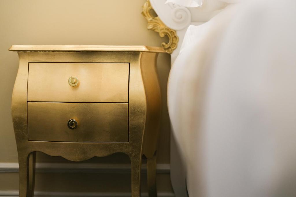 a gold nightstand next to a bed with a white sheet at B&B Kingsman in Florence