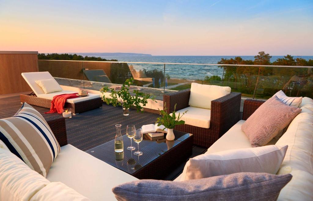 eine Terrasse mit Korbmöbeln und Meerblick in der Unterkunft Strandresort Prora - Penthouse 504 mit Meerblick und Sauna in Binz