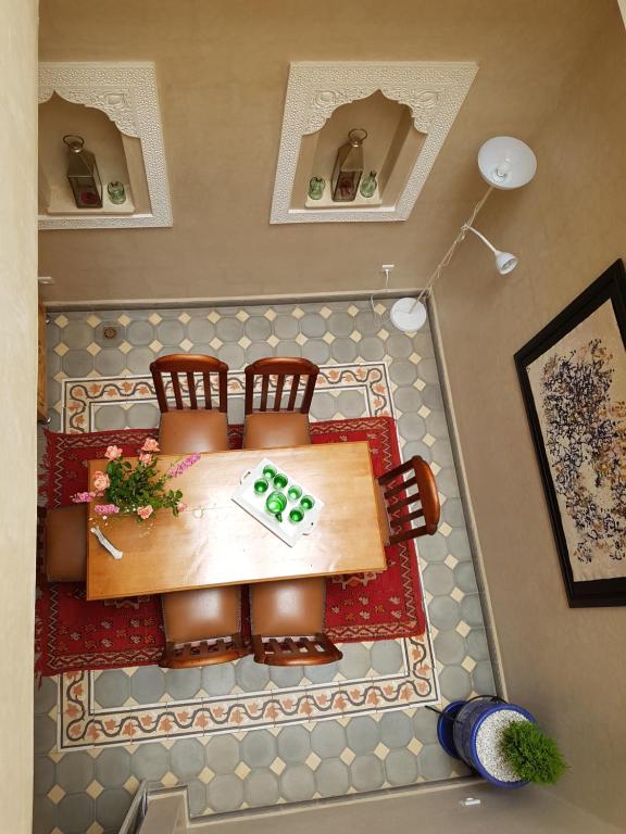 uma mesa com duas cadeiras e uma mesa com um quadro com uma triítimetria de escrita em Riad Espressino Marrakech em Marrakech