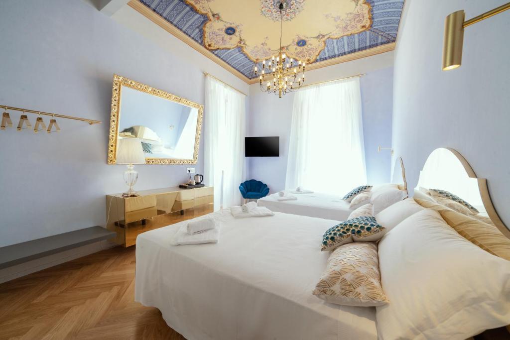 a bedroom with a large white bed with a chandelier at Palazzo dei Grifoni - Luxury Suites - in San Benedetto del Tronto