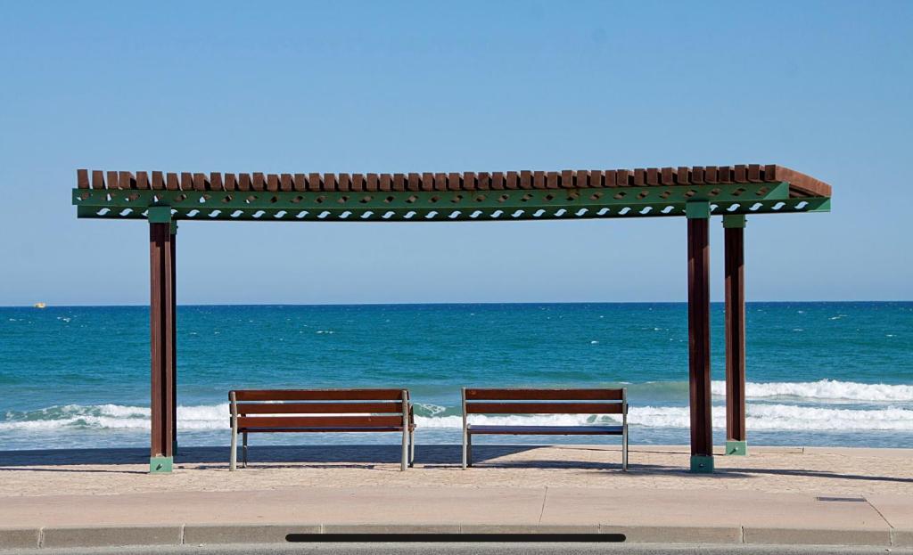 zwei Bänke unter einem Pavillon am Strand in der Unterkunft Super Apartamento en playa de la Pineda in La Pineda