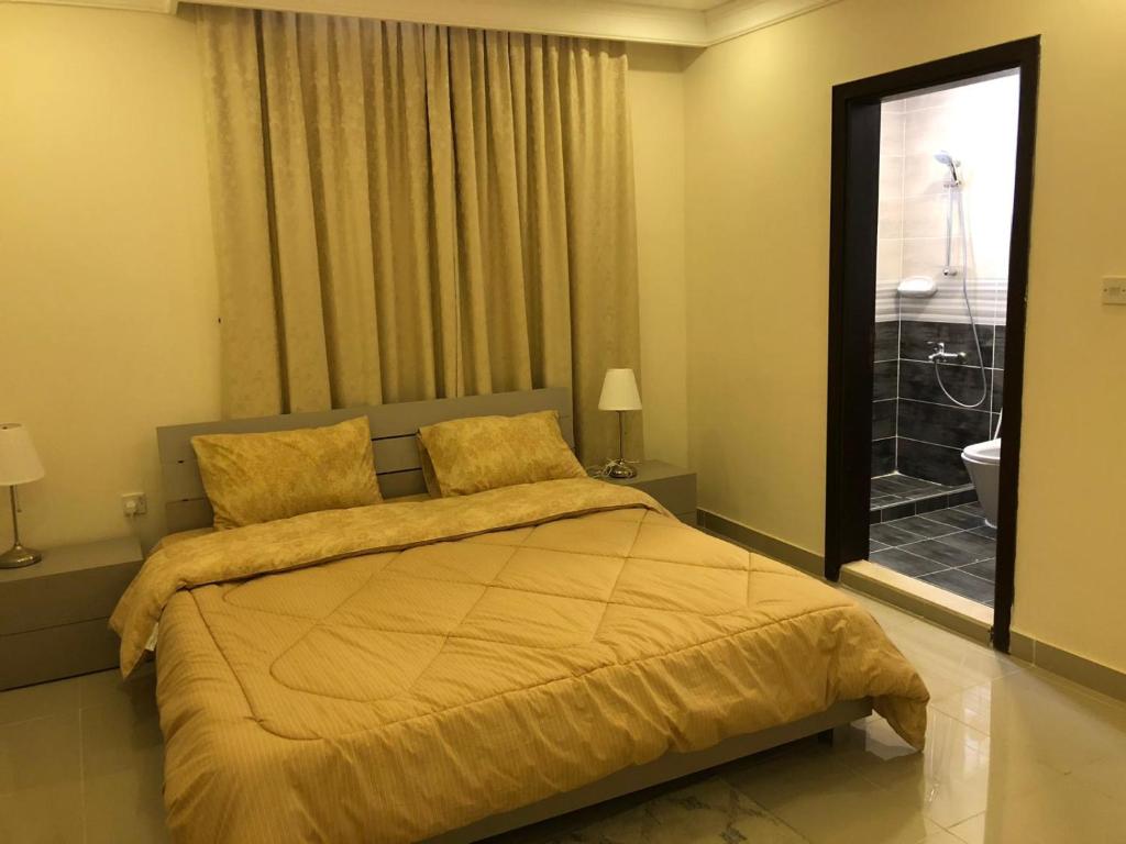 a bedroom with a bed and a window with a bathroom at The Diamonds (Families Only ) in Al Khīrān