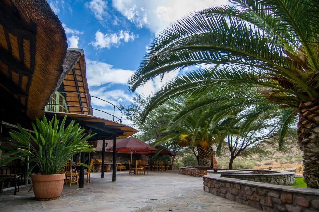 un patio con palmeras y un edificio en Etusis Lodge, en Usakos