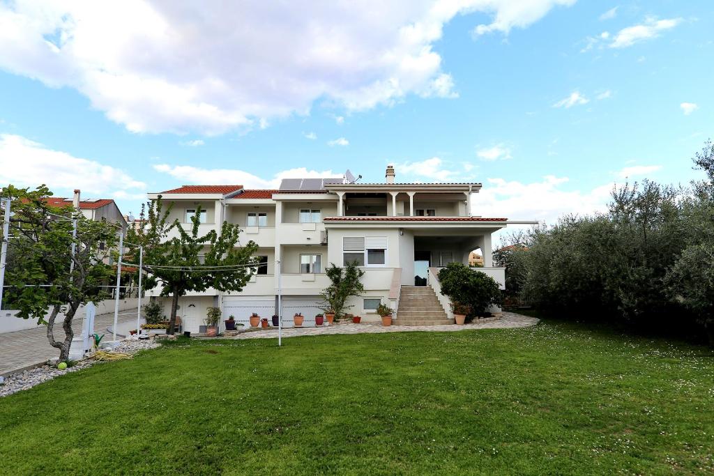 a large white house with a grass yard at Villa Mičić in Zadar