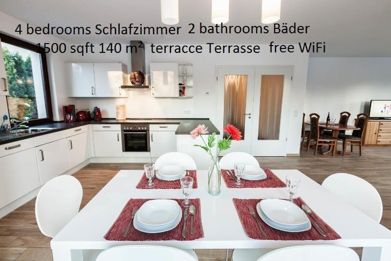 a white kitchen with a white table with white chairs at Ferienwohnung Niederschönhausen in Berlin