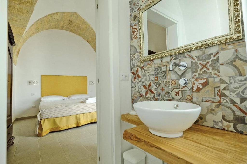 La salle de bains est pourvue d'un lavabo et d'un lit avec un miroir. dans l'établissement Corte Scarcia, à Ugento