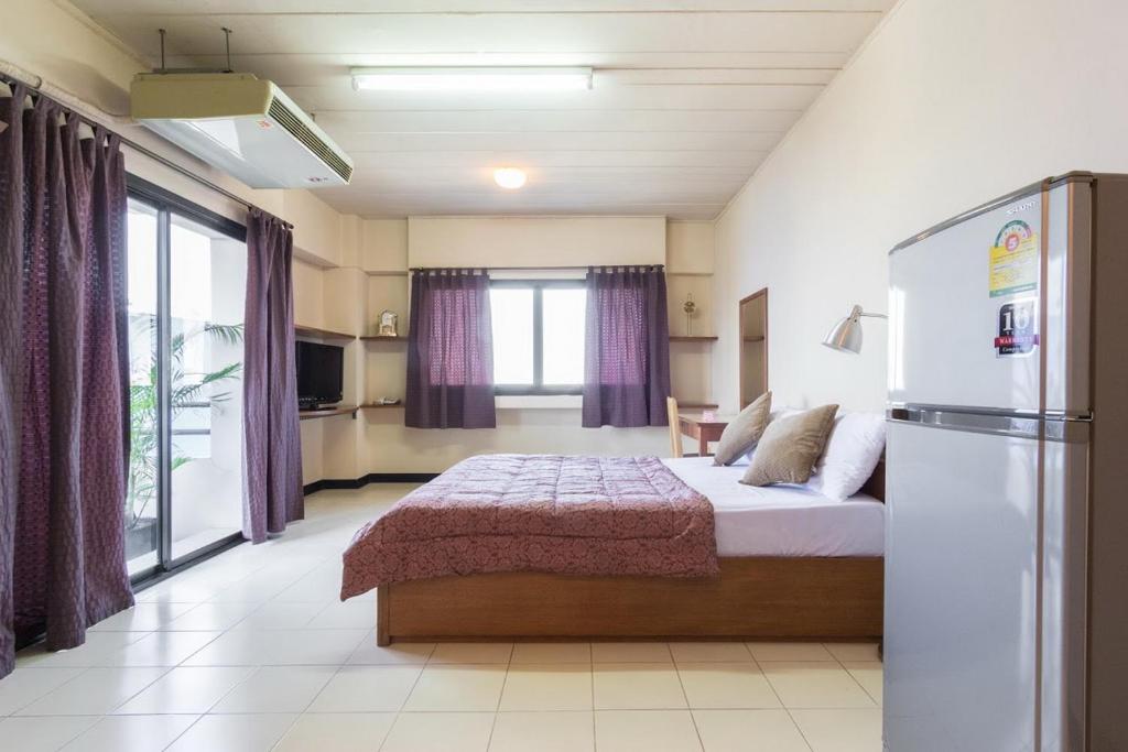 um quarto com uma cama grande e um frigorífico em Grand Residence Ngamwongwan 19 em Nonthaburi