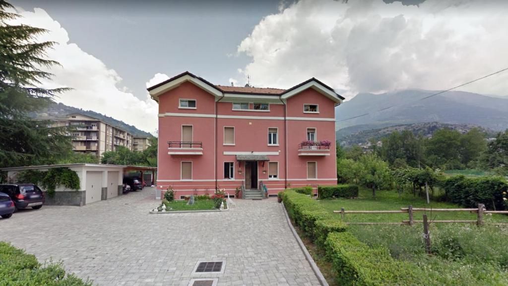 une grande maison rose dans un parking dans l'établissement Al borgo di Sant'Orso - CIR 0342, à Aoste