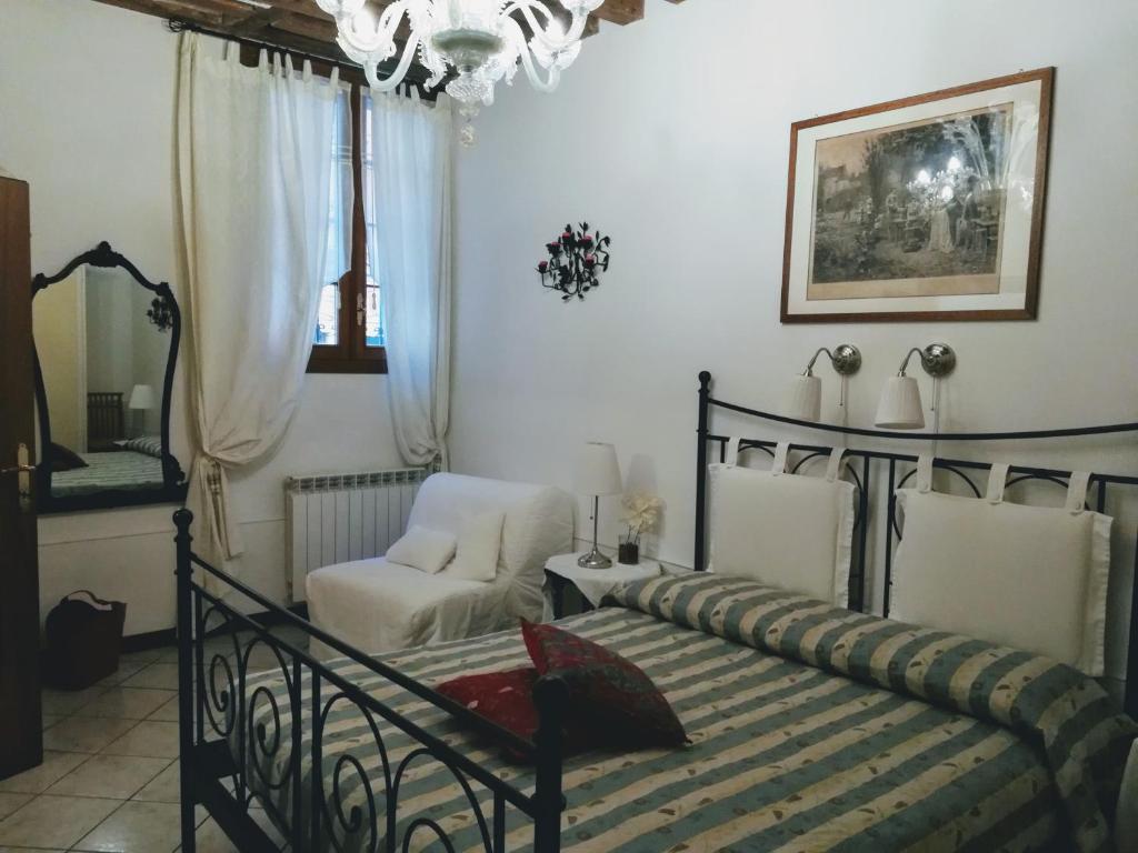 een slaapkamer met een bed, een stoel en een kroonluchter bij La Corte in Venetië