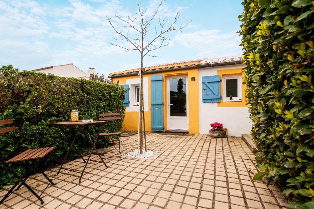 a patio with a table and a tree in front of a house at Les Yeux Bleus Bed &amp; Breakfast in Noirmoutier-en-l&#39;lle