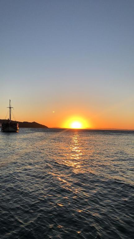 a boat on the water with the sunset in the background at Apartamento em João Fernandes - Búzios in Búzios