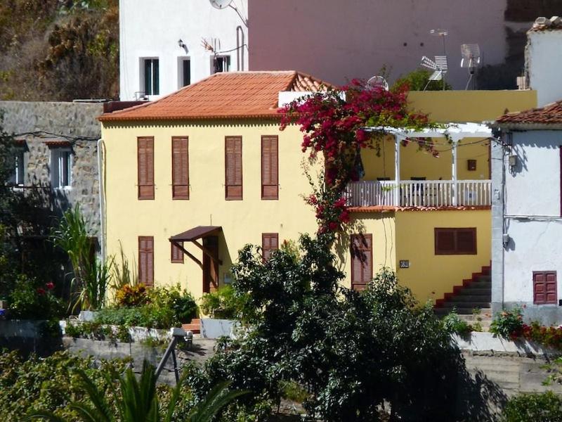 una casa amarilla con un balcón con flores. en Casa Rural Lili en Vallehermoso