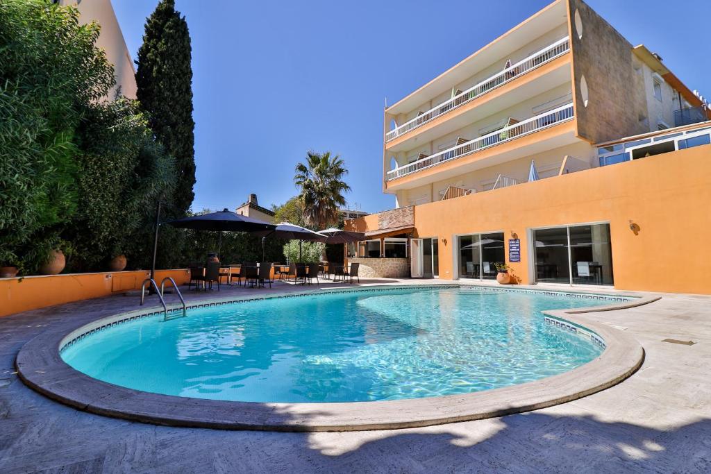 a swimming pool in front of a building at Hôtel Restaurant de la Mer in Golfe-Juan