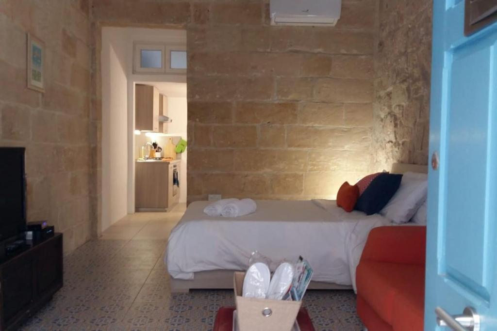 een slaapkamer met een bed en een bakstenen muur bij Zekka Studio in Valletta