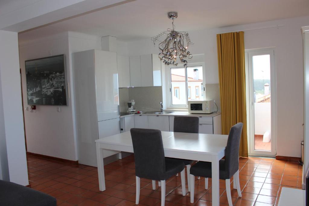 een keuken met een witte tafel en stoelen bij Flats - Duna Parque Group in Vila Nova de Milfontes