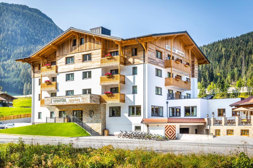 ein großes weißes Gebäude mit einem Holzdach in der Unterkunft OFENTÜRL alpine living in Flachau