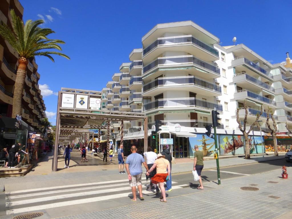 a group of people crossing a street in front of a building at Apartamentos Salou Centro in Salou