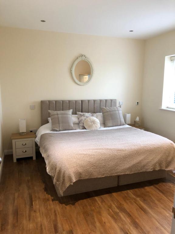 a bedroom with a large bed and a mirror at Spring Hill Cottages in Towcester