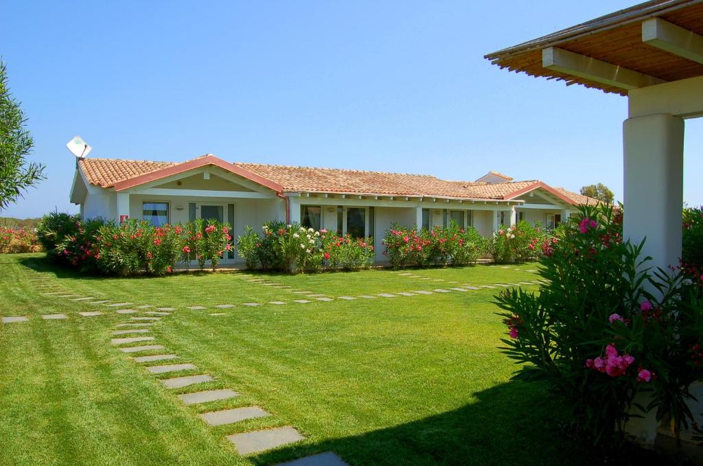 a house with a green yard with flowers at Hotel Budoni Beach in Budoni