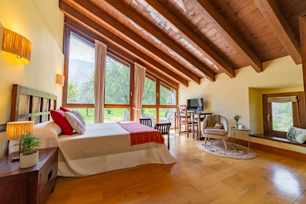 a bedroom with a bed in a room with windows at Hotel Rural El Pandal in Ardisana