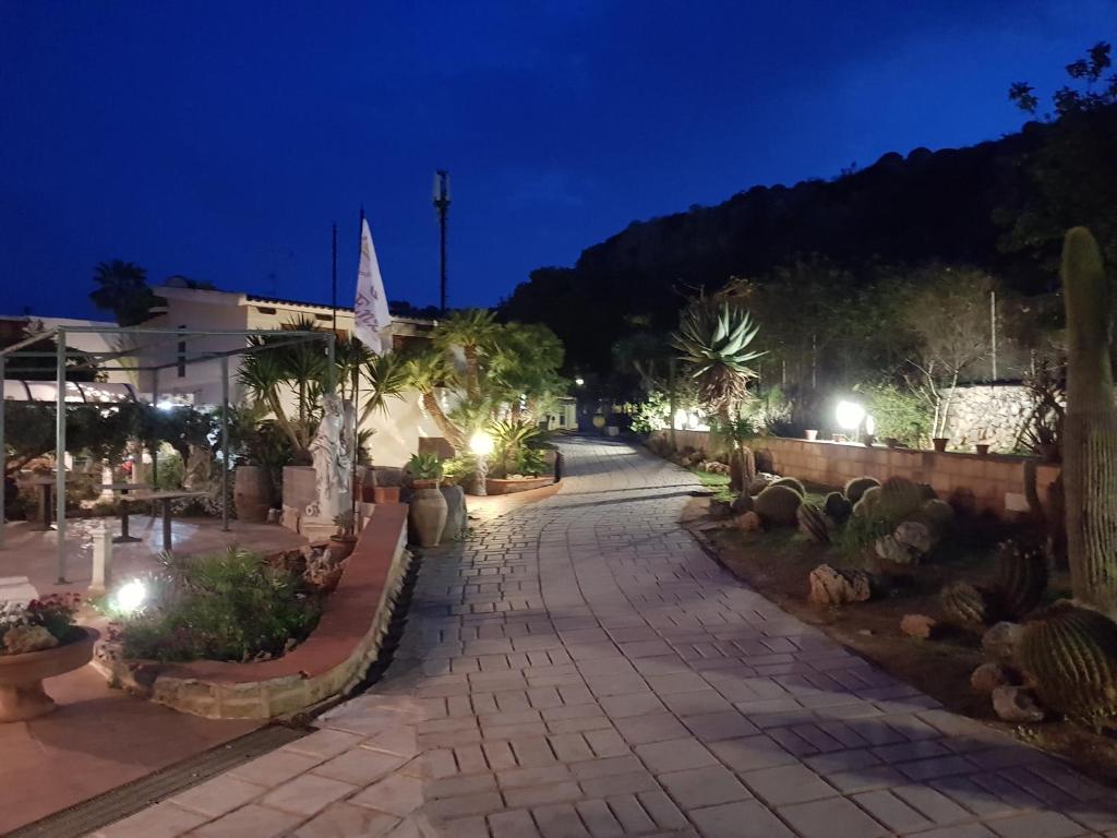 Una pasarela con plantas y luces por la noche en Federico Re, en San Vito lo Capo