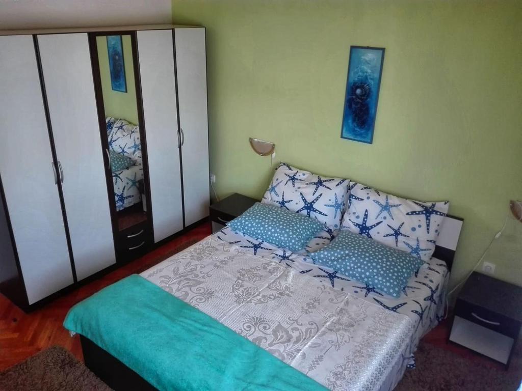 Schlafzimmer mit einem Bett mit blauen und weißen Kissen in der Unterkunft Apartment Tičić in Povljana