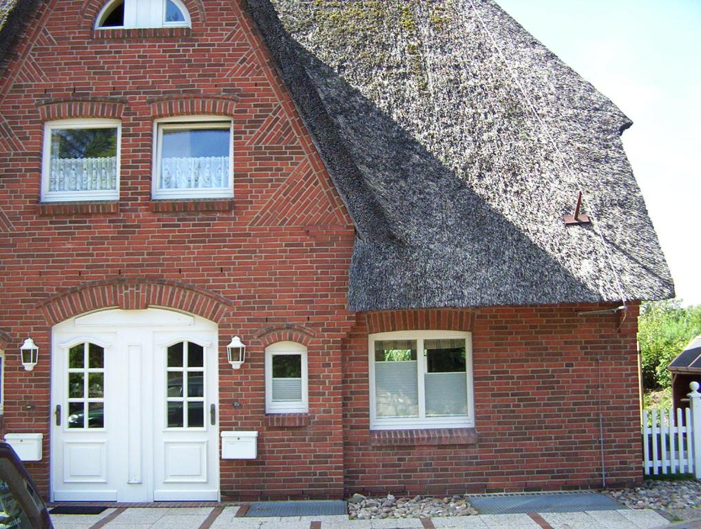 a red brick house with a white door at Ferienwohnung Roman in Tinnum