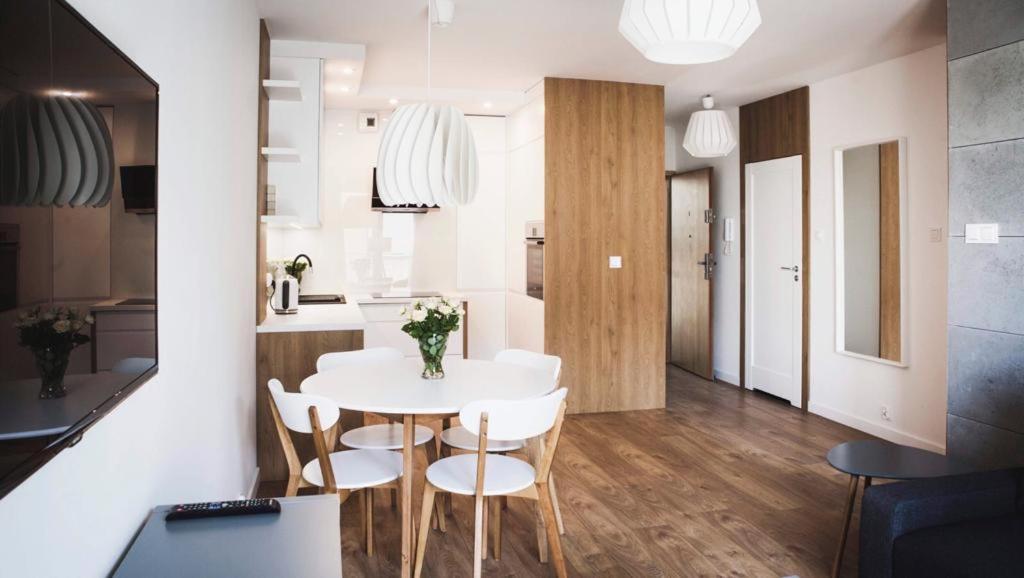 Una cocina y un comedor con una mesa y sillas blancas. en Apartament w centrum Olsztyna - Grunwaldzka, en Olsztyn