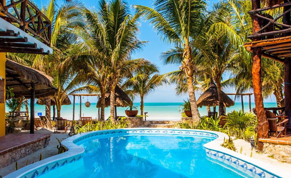 een zwembad van het resort met palmbomen en het strand bij Holbox Dream Beachfront Hotel in Holbox Island
