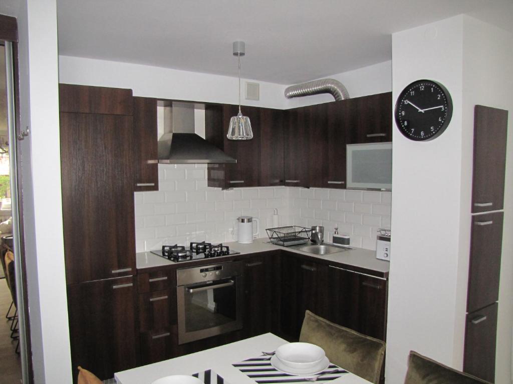 a kitchen with wooden cabinets and a clock on the wall at Apartament Okrzei in Kłodzko