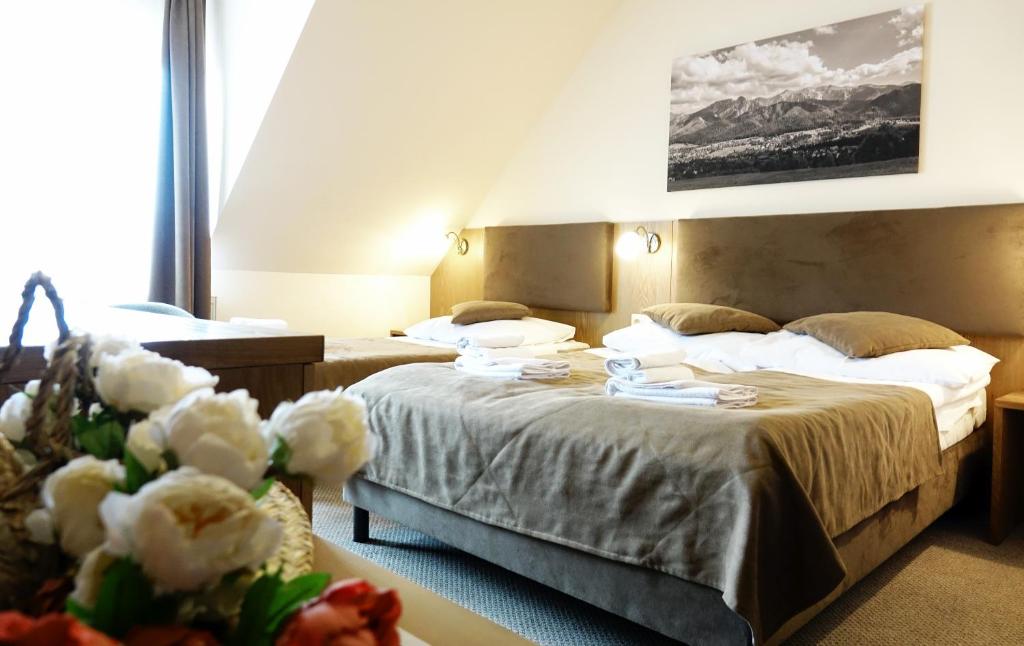 um quarto de hotel com duas camas e uma mesa com flores em ZAJAZD BIAŁCZAŃSKI Dom Wypoczynkowy Restauracja em Białka Tatrzanska