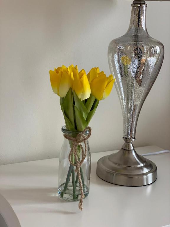 a vase with yellow flowers in it next to a vase with a lamp at Burrowlodge in Kilfenora