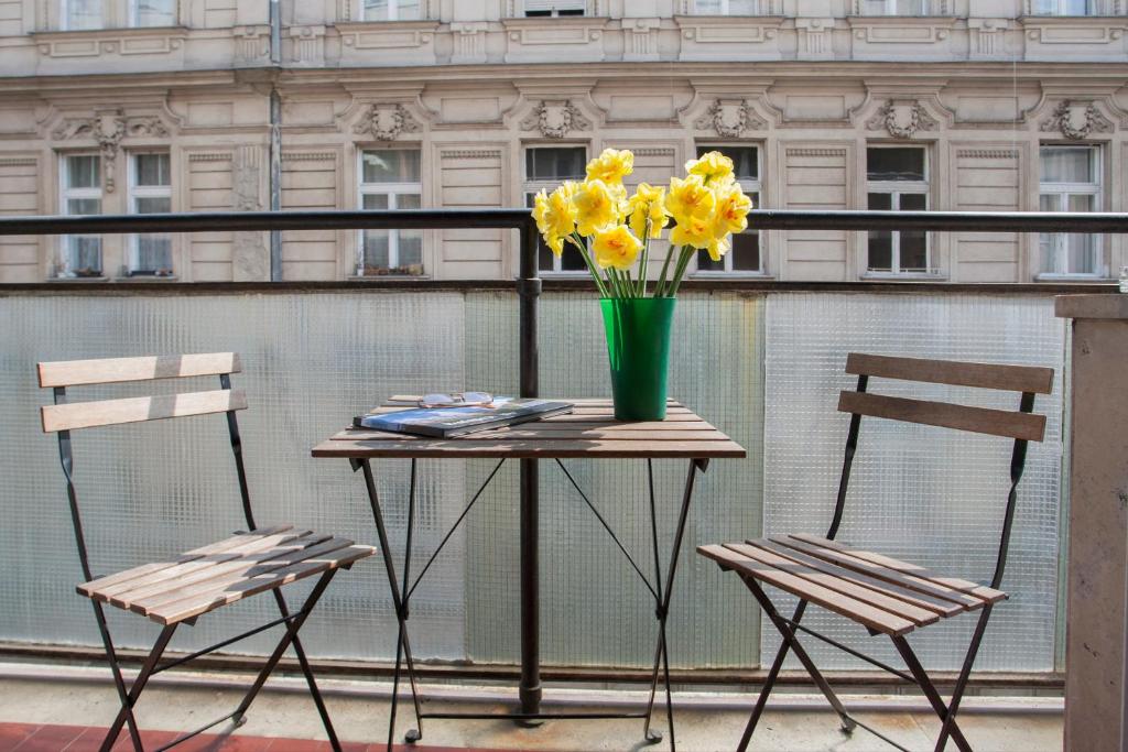 un tavolo con due sedie e un vaso di fiori gialli di Katrin Apartment a Budapest