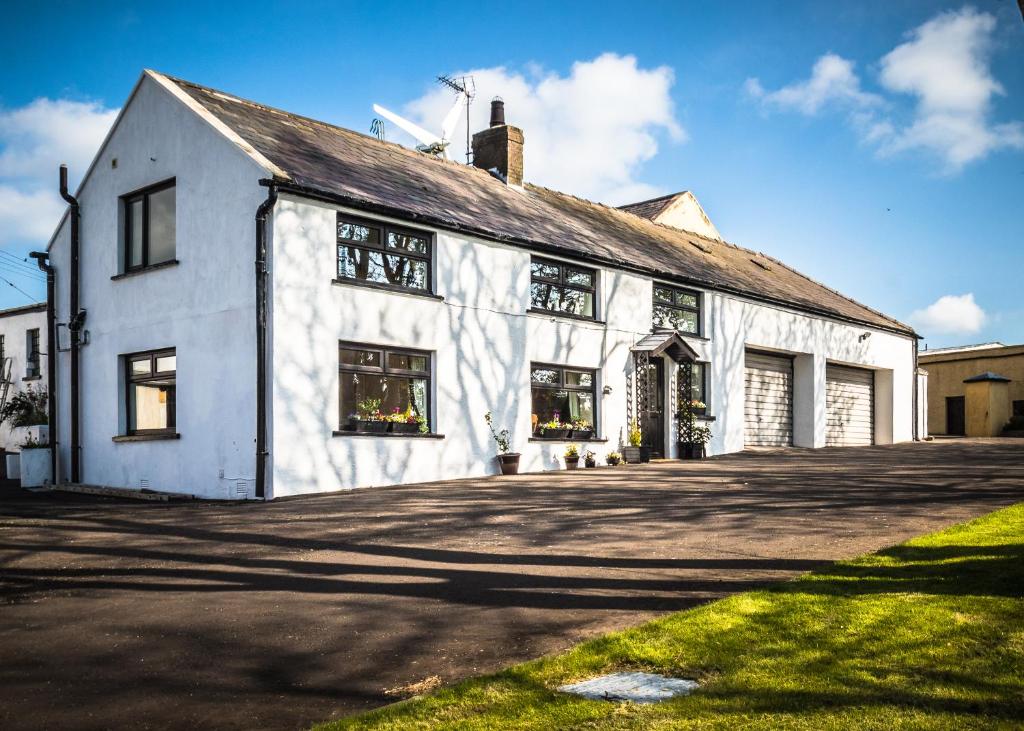 a white building with windows on the side of it at Mallard Cottage in Whitehead