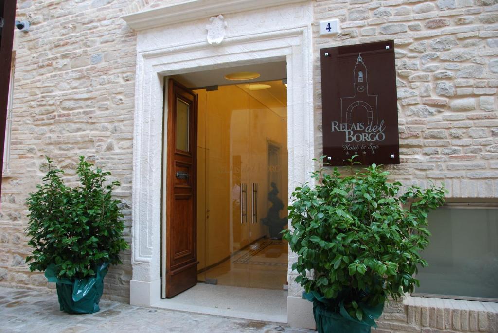 ein Gebäude mit zwei Topfpflanzen vor einer Tür in der Unterkunft Relais Del Borgo Hotel & Spa 4 Stelle in Staffolo