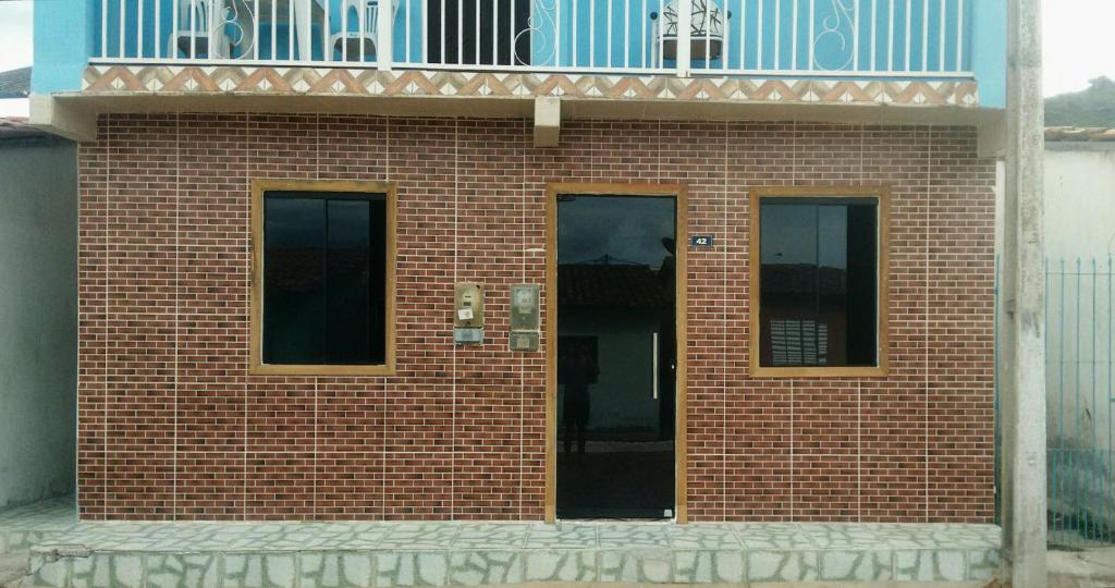 a red brick building with a balcony on top at Casa da Sua Família in Mucugê