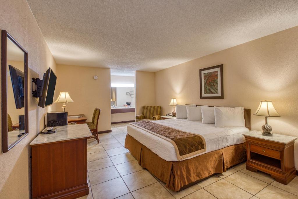 Habitación de hotel con cama grande y escritorio. en Palms Garden Inn en Ellisville