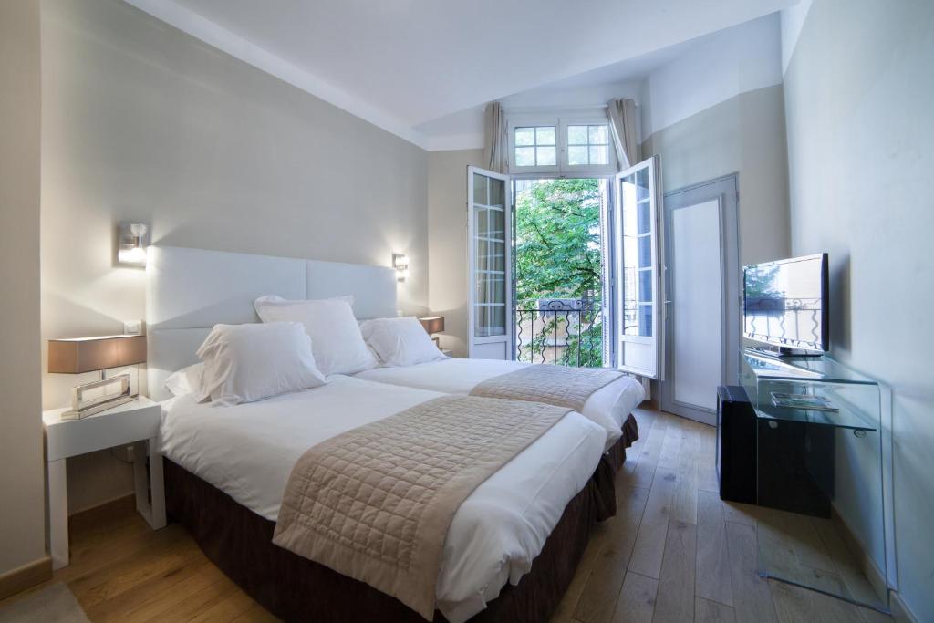 - une chambre avec un grand lit et une télévision dans l'établissement Hôtel de France, à Aix-en-Provence