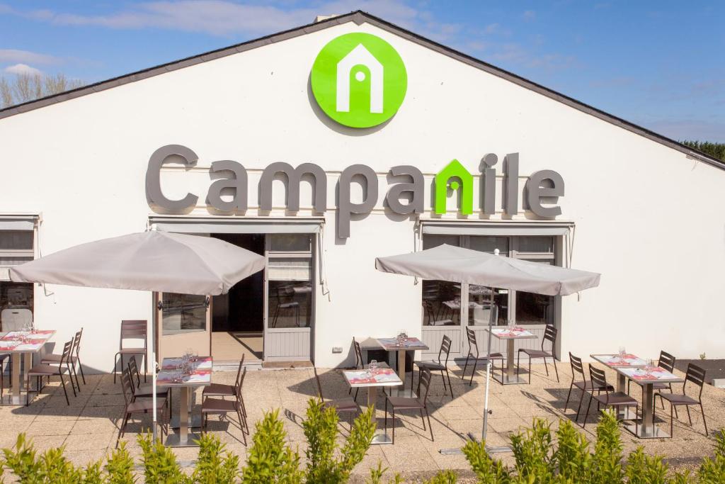 un bâtiment avec des tables et des parasols devant lui dans l'établissement Campanile Poitiers, à Poitiers