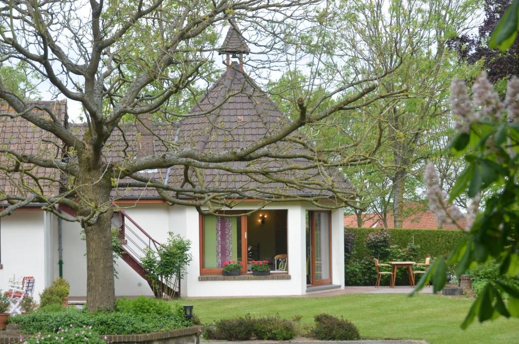 a white house with a tree in the yard at La Coulonnière in Wismes