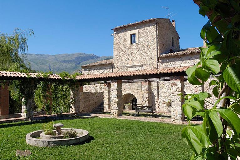 un grand bâtiment en pierre avec une fontaine dans une cour dans l'établissement Giardino Donna Lavia, à Polizzi Generosa